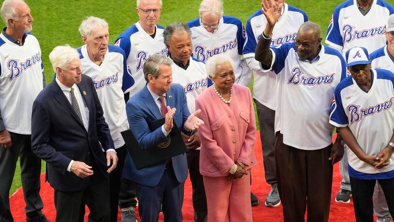 Billye Aaron, wife of the late Hank Aaron stands with Georgia Gov. Brian Kemp, second from left, Atlanta Braves chairman and CEO Terry McGuirk, left, Dusty Baker, right and players from the 1974 Atlanta Braves team during a ceremony to mark the 50th anniversary of Aaron breaking Babe Ruth's home run record team before a baseball game against the New York Mets Monday, April 8, 2024, in Atlanta. (AP Photo/John Bazemore)