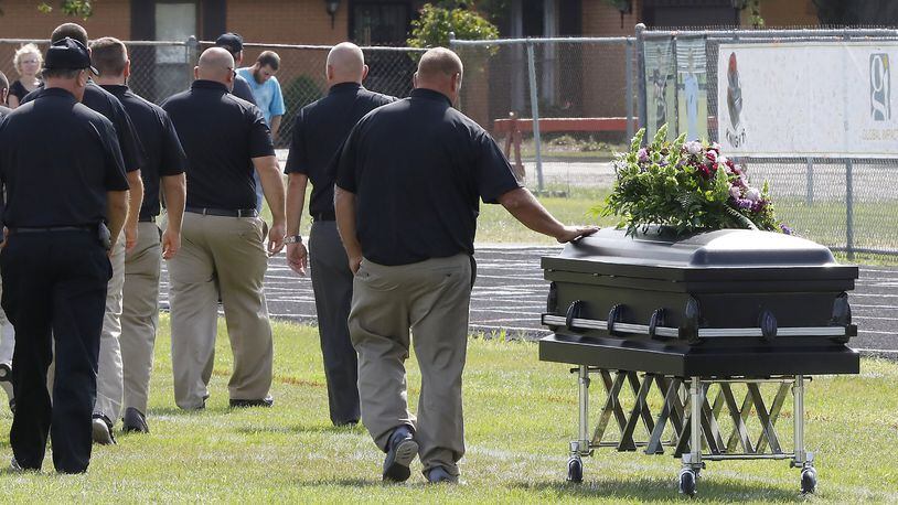 One of the Greenon High School football coaches touches Connor Williams’ casket as the coarches walk off the field after speaking during a joint funeral for student athletes Connor and David Waag at school’s football stadium Friday. Connor and David were killed in a car accident last Sunday. Bill Lackey/Staff