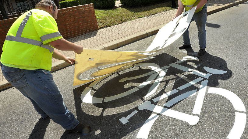 David Adkins, left, and Stephen Bowers from the City of Springfield touch up the bicycle crossing sign on South Fountain Avenue Thursday. Bill Lackey/Staff