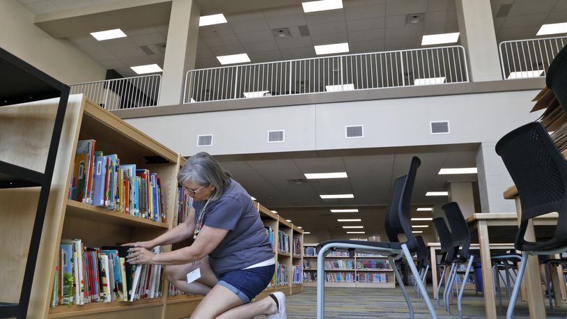 Carlye Stewart, a librarian in the new Kenton Ridge School, sets up a book shelf in the school's library Friday, August 4, 2023. BILL LACKEY/STAFF