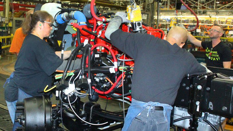 Navistar International employees work on the assembly line putting an engine in a new truck in 2018.