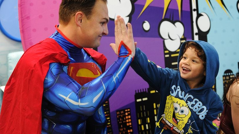 Messiah Stinson, age 3, high-fives Superman on Wednesday, Jan. 31, 2024 at the 11th annual Superhero Day at Dayton Children’s Hospital. The tradition honors a patient who loved superheroes. The event recognizes other superheroes too — the patients, families, caregivers and staff at Dayton Children’s Hospital. MARSHALL GORBY\STAFF