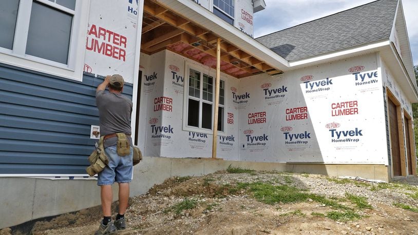 A construction worker attaches vinyl siding to the outside of a house under construction in the Northridge area. Bill Lackey/Staff