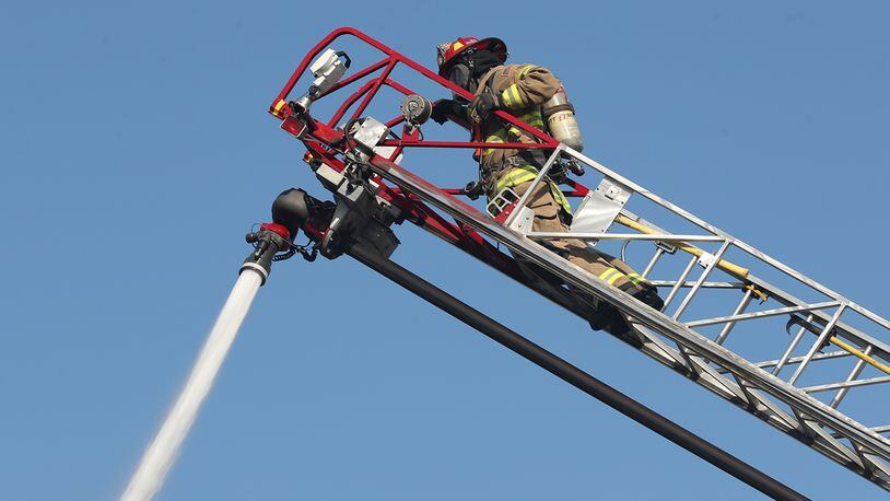 A Springfield Fire Division firefighter hoses down flames of a structure fire. BILL LACKEY/STAFF