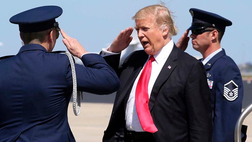 President Donald Trump, center, salutes the U.S. Air Force security detail at Orlando International Airport during his arrival to visit to St. Andrew Catholic School in Orlando, Fla., Friday, March 3, 2017. (Joe Burbank/Orlando Sentinel via AP)