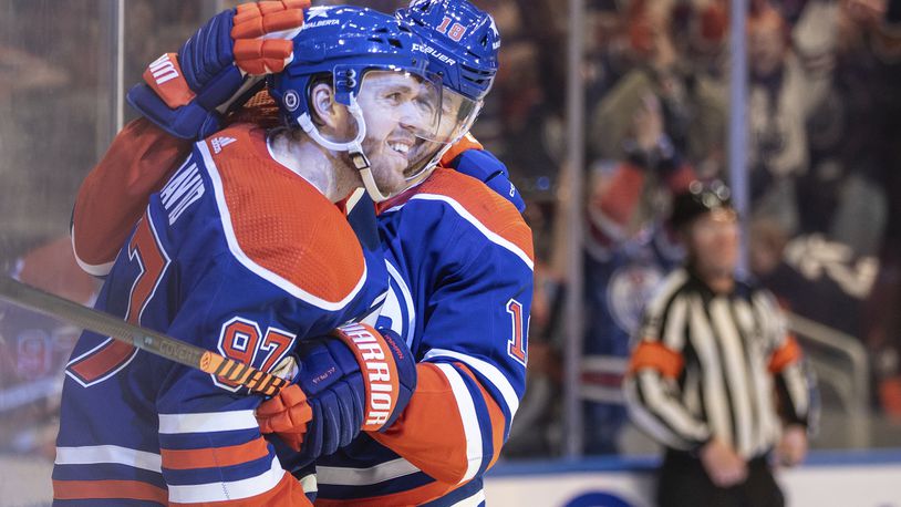 Edmonton Oilers' Connor McDavid (97) celebrates his 100th assist this season with Zach Hyman (18) against the San Jose Sharks during the second period of an NHL hockey game in Edmonton, Alberta, on Monday, April 15, 2024. (Jason Franson/The Canadian Press via AP)