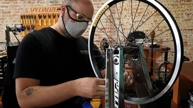 Jon Francis, the owner of Cyclotherapy, working on a clients bicycle wheel Thursday. He was a finalist in the Springfield Hustles competition last year. BILL LACKEY/STAFF