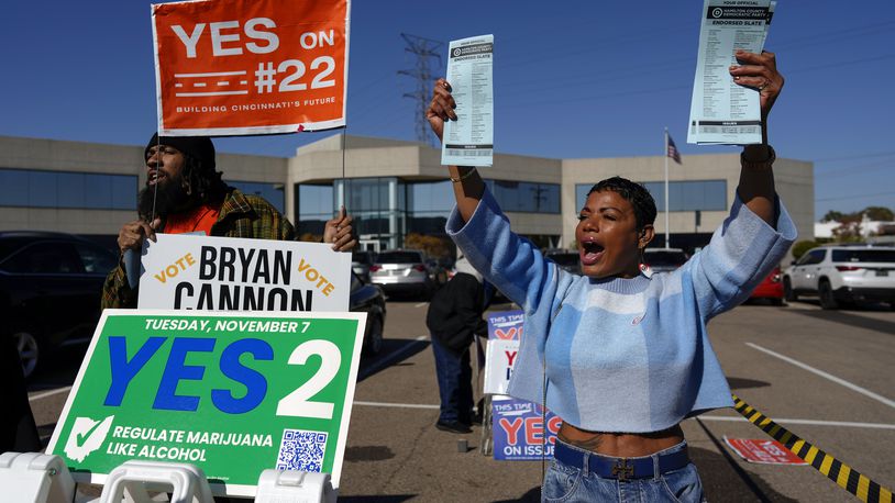 Nikko Griffin, left, and Tyra Patterson, call out to arriving voters in the parking lot of the Hamilton County Board of Elections during early in-person voting in Cincinnati, Thursday, Nov. 2, 2023. They urge people to vote for different issues, including Issue 2, which would allow adult-use sale, purchase, and possession of cannabis for Ohioans who are 21 and older. They also pass out Hamilton County Democratic Party sample ballots. Ohioans will decide next week on whether to legalize recreational marijuana, but people on both sides of the issue say more hangs in the balance than simply decriminalizing the drug. (AP Photo/Carolyn Kaster)
