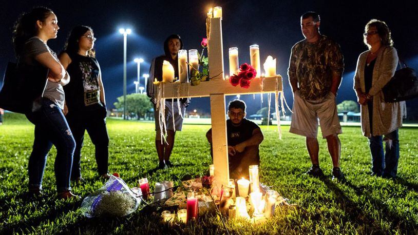 People visit one of seventeen crosses following a candlelight vigil for the victims of the shooting at Marjory Stoneman Douglas High School in Parkland on Feb. 15. Gov. Rick Scott has called for more law enforcement officers in schools, but that will take time, a Palm Beach County School Police official said Tuesday. (Greg Lovett / The Palm Beach Post)