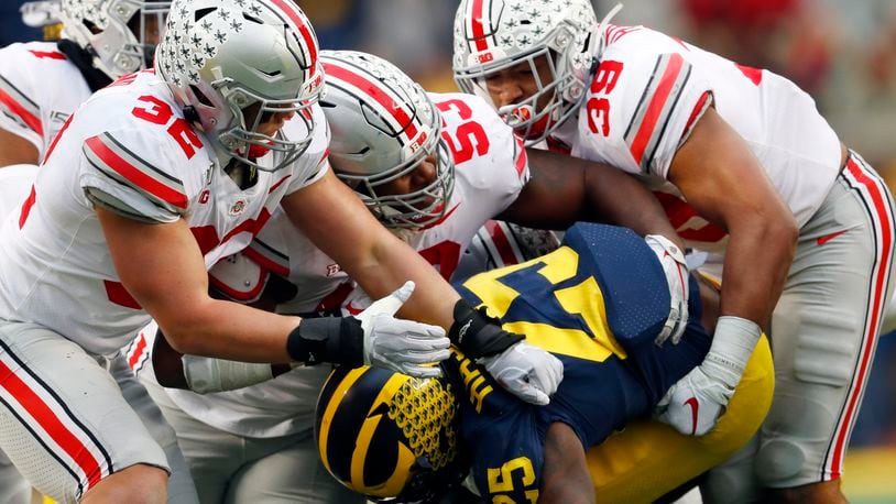 FILE - Ohio State linebackers Tuf Borland (32), Davon Hamilton (53) and Malik Harrison (39) smother Michigan running back Hassan Haskins (25) in the second half of an NCAA college football game in Ann Arbor, Mich., in this Saturday, Nov. 30, 2019, file photo. Michigan canceled its annual rivalry game at Ohio State on Tuesday, Dec. 8, 2020, because of the COVID-19 outbreak within the Wolverines football program. (AP Photo/Paul Sancya, File)