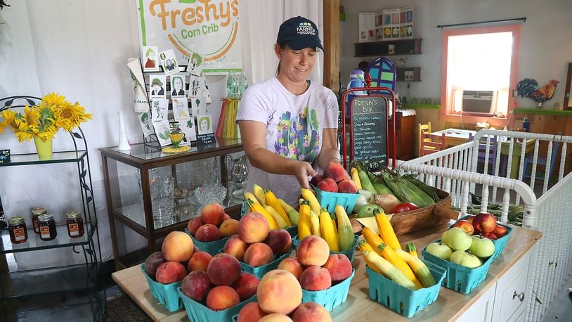 Elizabeth Thompson sets out fresh produce in Freshy's Corn Crib Friday, July 29, 2022. BILL LACKEY/STAFF