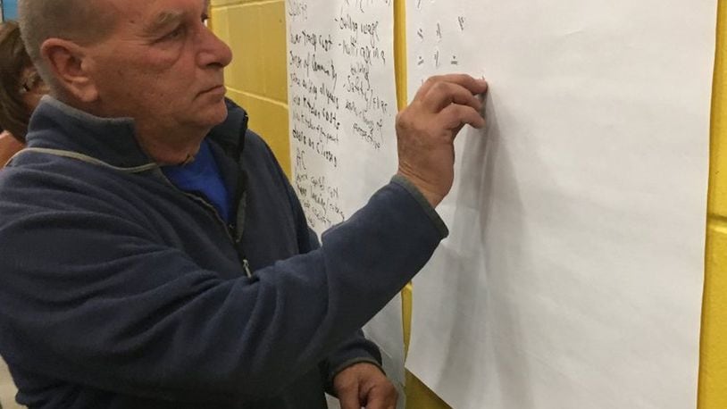 A Northeastern resident is shown putting one of his three stickers on option two during a school forum held two weeks ago. The option, to build two PreK-12 buildings, was the number one choice but those who attended the meeting.
