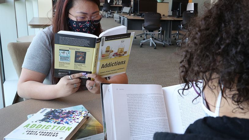 Clark State College students Gracie Perkins, left, and Jasmin Alford study about addiction in the Clark State Library. BILL LACKEY/STAFF