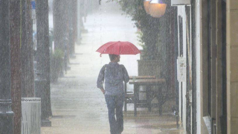 A pedestrian tries to keep dry on Clematis Street. (Lannis Waters / The Palm Beach Post)