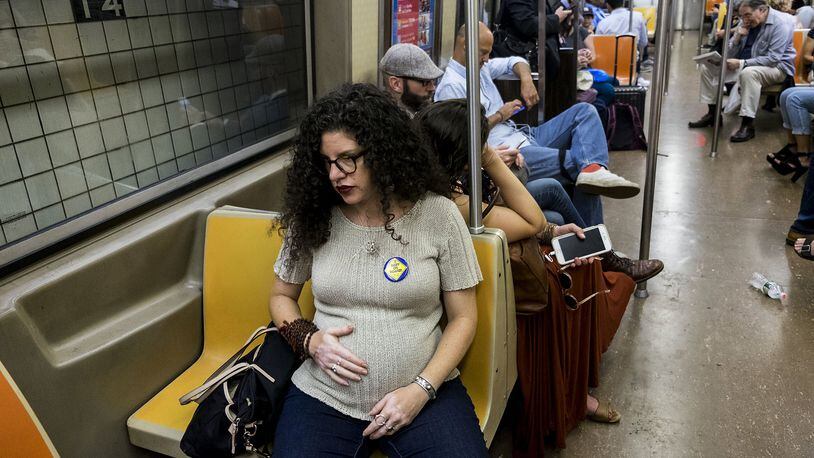 Jamie Tzioumis commutes wearing a “Baby on Board” button, in New York City, Sept. 20, 2017. The button is part of a new campaign by the Metropolitan Transportation Authority to encourage commuters to give up seats for passengers who are pregnant, older or have a disability. Does the button work on a crowded train? According to Tzuioumis, who is six months pregnant, not really. CHRISTIAN HANSEN/THE NEW YORK TIMES