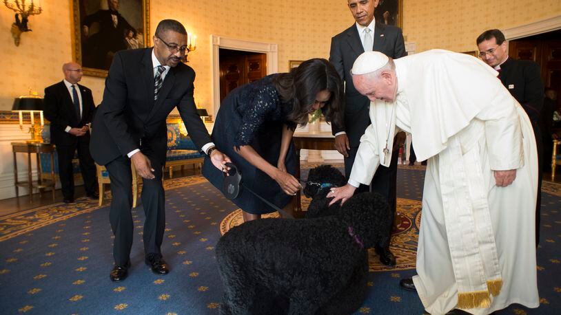 In this photo provided by L'Osservatore Romano, Pope Francis and first lady Michelle Obama pet the Obama's dogs as President Barack Obama looks at the White House in Washington, Wednesday, Sept. 23, 2015. (L'Osservatore Romano via AP)