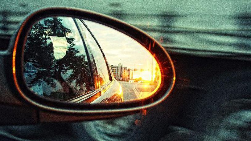 Photo illustration of a rear-view mirror of a moving car.