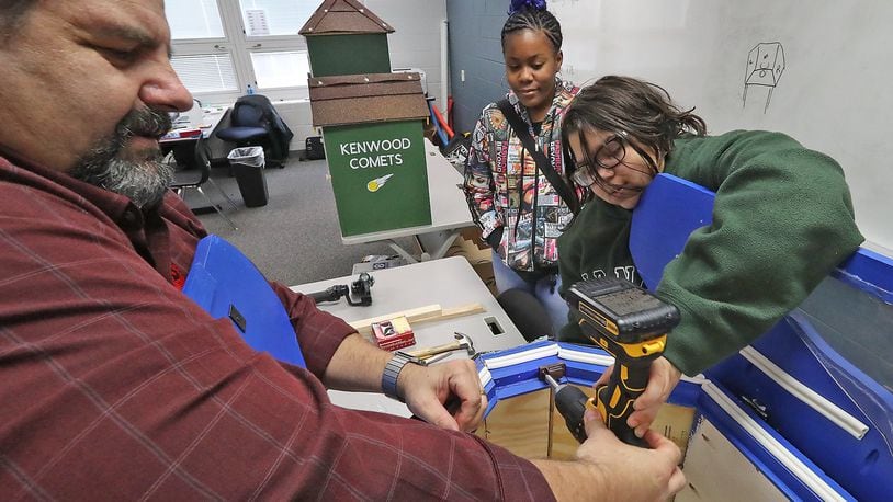 Hayward Middle School teacher, David Zeller, helps eighth graders, Natajha Castle, right, and Kailyn Greenip attach a door magnet on the “House of Knowledge” that they and the other students in Zeller’s design and modeling class made. Bill Lackey/Staff