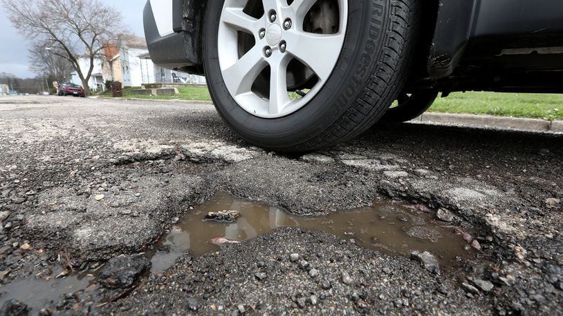 A car drives past a pothole along Race Street Monday, April 16, 2018. City of Springfield has announced plans to repave several city streets. It will use money from a levy passed in Springfield in 2017.