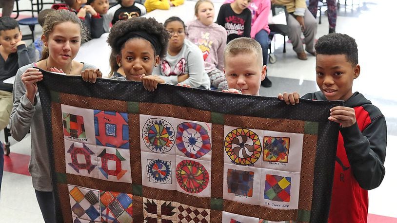 Four students in the after school program at Lincoln Elementary prepare to turn around and reveal the Freedom Quilt that the students in the program made as part of Black History Month Monday. The students each made a square for the quilt but Monday was the first time they had seen it all put together. The quilt will be on display near the office at the school. Bill Lackey/Staff