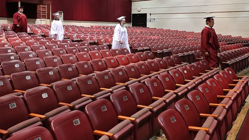 Members of the Urbana High School Class of 2020 march down the isle in an empty auditorium Tuesday. Video was taken of the students marching in their cap and gown to be edited together for a virtual graduation ceremony since they couldn’t have a real ceremony due to the coronavirus. BILL LACKEY/STAFF