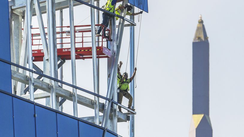 Atlanta construction workers move glass into place on the face of the rising Spring @ 8th, the new corporate headquarters for NCR Corp., in this July 2017 photo. JOHN SPINK/JSPINK@AJC.COM.