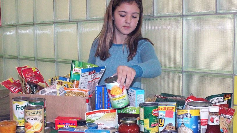 South Vienna School seventh grade student Trinity Ridgeway puts food items in the collection gathered by her peers. JEFF GUERINI/STAFF