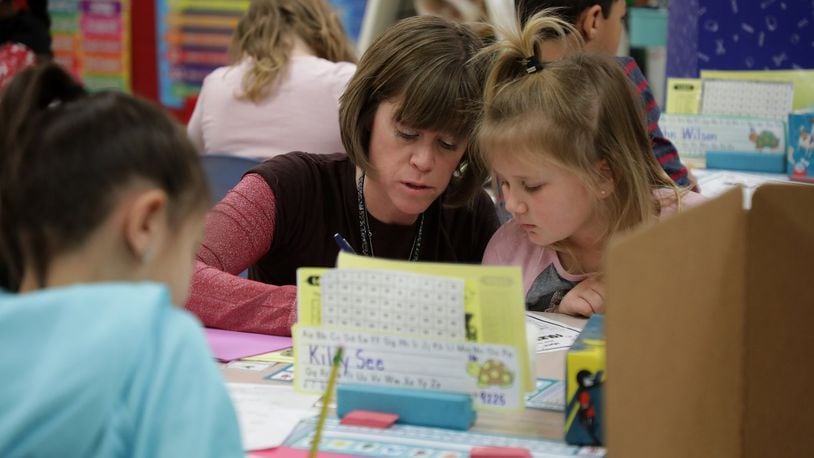 Second grade teacher Heidi Kottmyer helps students in her class at Donnelsville Elementary Friday. BILL LACKEY/STAFF