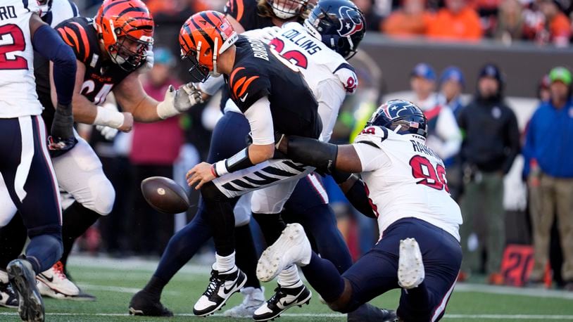 Cincinnati Bengals quarterback Joe Burrow, center, fumbles the ball as he is hit by Houston Texans defensive tackle Sheldon Rankins (98) during the second half of an NFL football game Sunday, Nov. 12, 2023, in Cincinnati. The Bengals recovered the fumble. (AP Photo/Michael Conroy)
