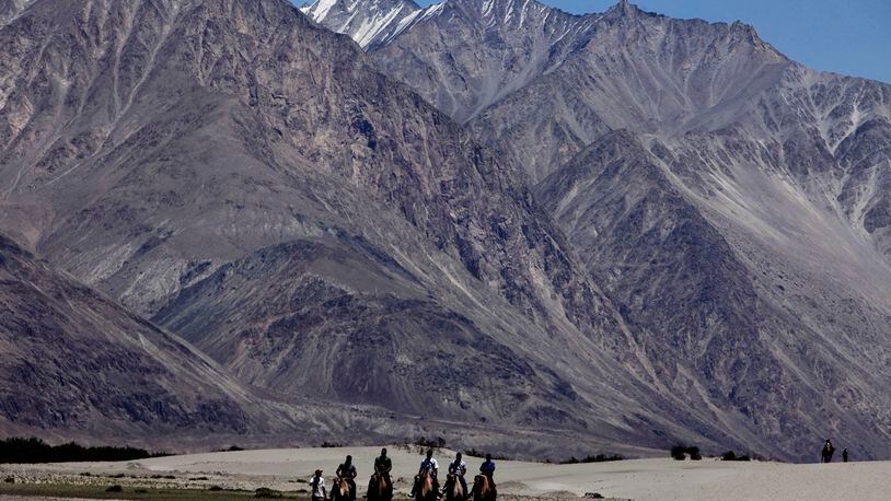 FILE- In this July 20, 2011 file photo, tourists ride double hump camels at Nubra valley, in Ladakh, India. Tensions along the disputed India-China border seem to be getting worse rather than better, three months after their deadliest confrontation in decades in June. The Asian giants accused each other this week of sending soldiers into each other’s territory and fired warning shots for the first time in 45 years, raising the specter of full-scale military conflict. (AP Photo/Channi Anand, File)