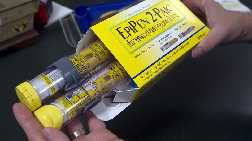 In this July 8, 2016, file photo, a pharmacist holds a package of EpiPens epinephrine auto-injector, a Mylan product, in Sacramento, Calif. (AP Photo/Rich Pedroncelli, File)