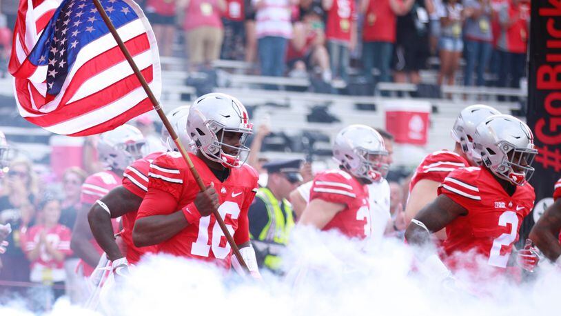 Ohio State's J.T. Barrett carries the flag onto the field before a game against Tulsa on Saturday, Sept. 10, 2016, at Ohio Stadium in Columbus. David Jablonski/Staff