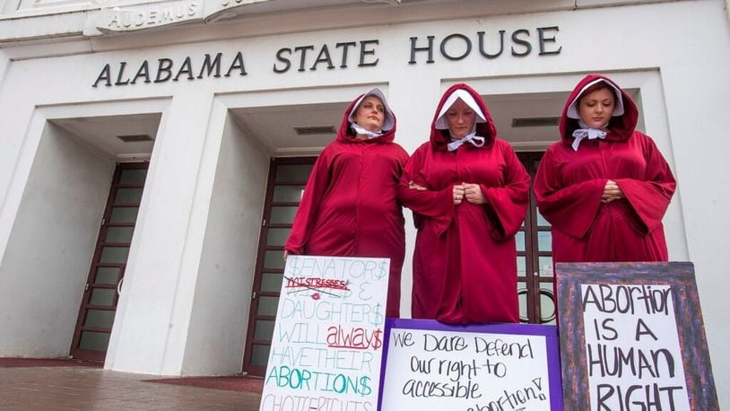 Bianca Cameron-Schwiesow, from left, Kari Crowe and Margeaux Hartline, dressed as handmaids, take part in a protest against HB314, the abortion ban bill, at the Alabama State House in Montgomery, Ala., on Wednesday April 17, 2019.