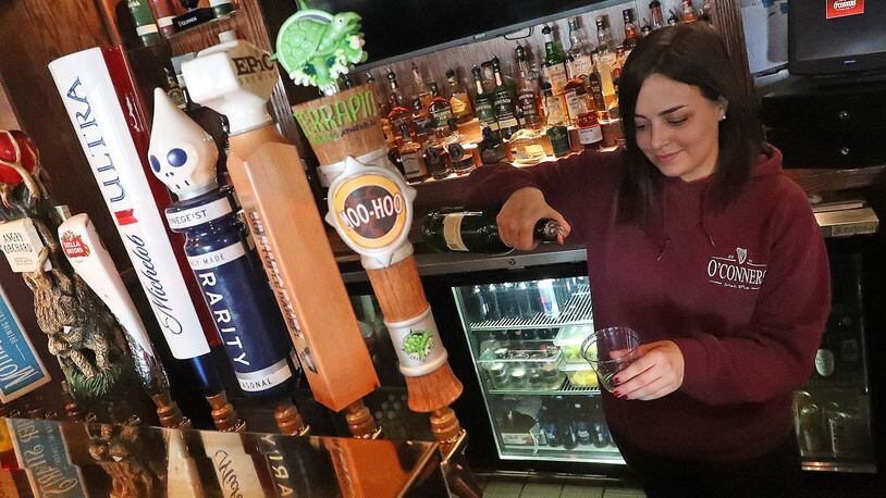 Ciera McDermott, a bartender at O’Conners Irish Pub, pours a customer a drink to-go Wednesday. BILL LACKEY/STAFF