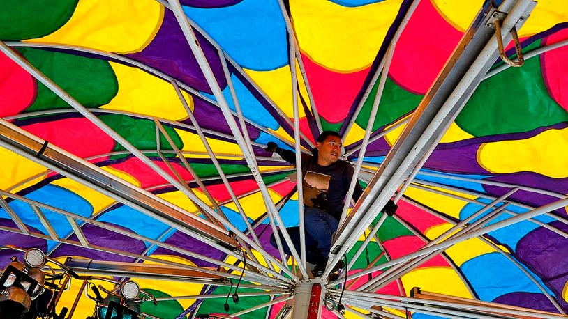 An employee of Chicketti Family Amusements sets up one of the amusement rides in front of Northeastern School on Thursday, Sept. 7, 2023, as he and his co-workers get ready for the South Vienna Corn Festival that starts Friday afternoon. BILL LACKEY/STAFF