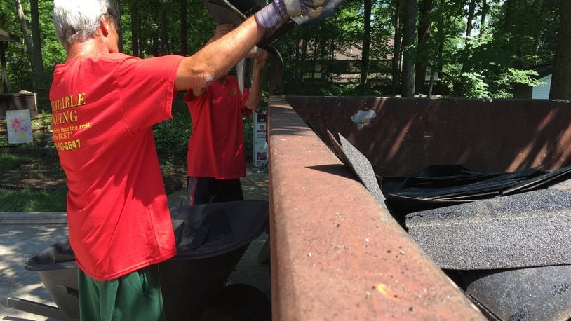 Workers with Dependable Roofing toss old shingles out. Staff Photo/Katherine Collins