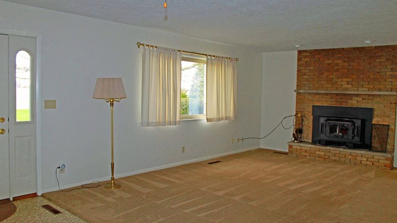 The living room features neutral carpeting and a wide picture window that floods the space with natural light.