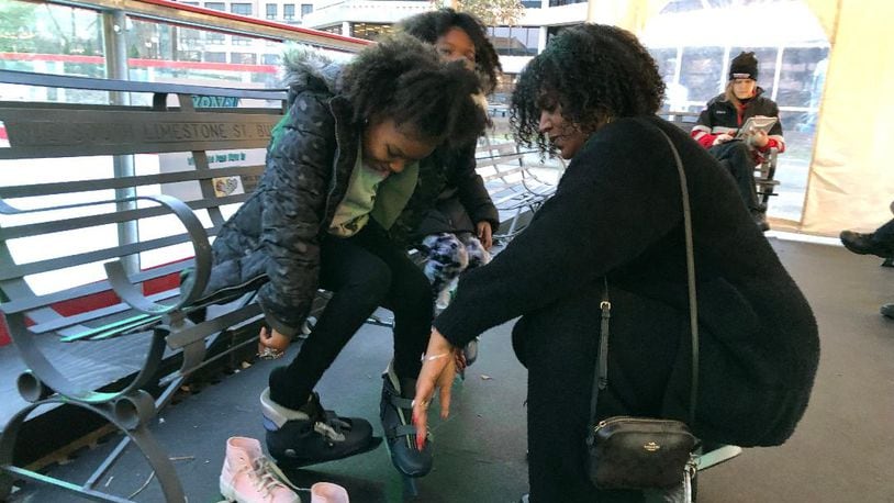 Candace Simmons helps her twins Kay'On and Kay'Lyn with their skates on Saturday at the Speedway Ice Skating Rink. Simmons said she didn't want a shooting incident that occurred Friday evening to interfere with the girls' excitement to skate.