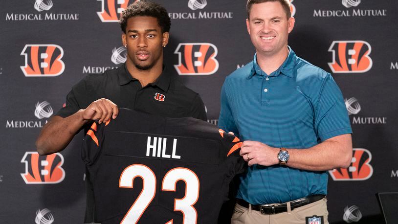 Cincinnati Bengals head coach Zac Taylor, right, holds up a team jersey with Daxton Hill for a photo after introducing Hill as the NFL football team's first-round pick during a news conference Friday, April 29, 2022, in Cincinnati. (AP Photo/Jeff Dean)