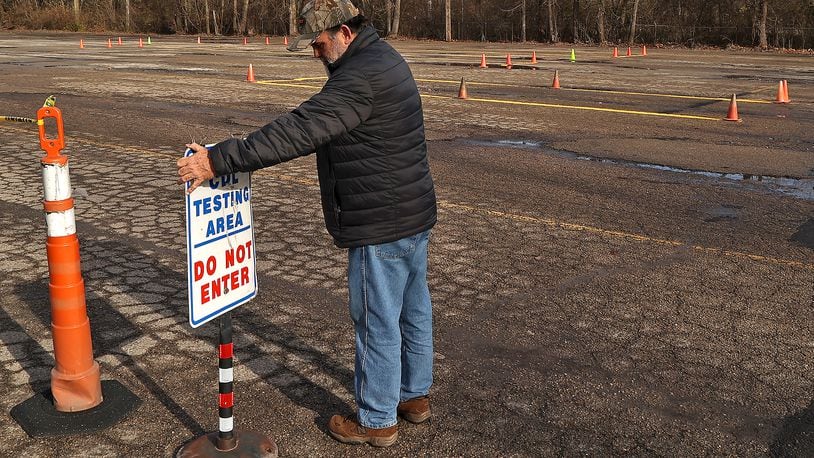 William Weekley, a Clark State instructor and CDL examiner, straightens a sign at the new testing facility on Tremont City Road. BILL LACKEY/STAFF