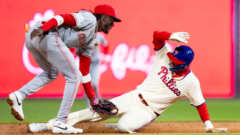 Cincinnati Reds shortstop Elly De La Cruz, left, tags out Philadelphia Phillies' Nick Castellanos on a steal attempt during the second inning of a baseball game Wednesday, April 3, 2024, in Philadelphia. (AP Photo/Chris Szagola)