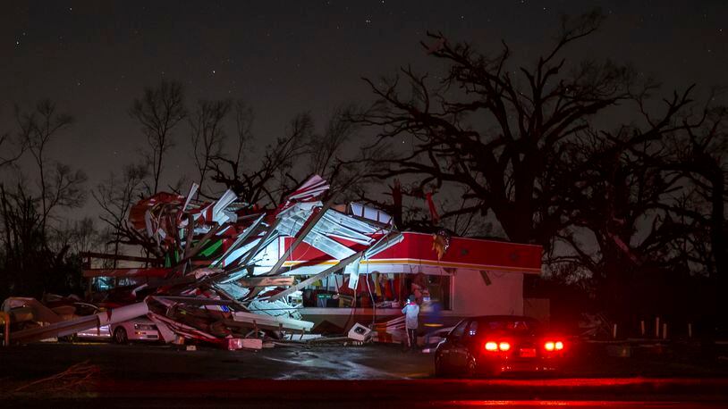 People stop to take a photo of a gas station damaged by an apparent tornado, Sunday, Jan. 22, 2017, in Albany, Ga. Nathan Deal declared a state of emergency in several counties, including Cook, that have suffered deaths, injuries and severe damage from weekend storms. (AP Photo/Branden Camp)