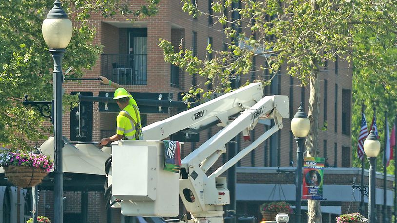 A city of Springfield worker hangs banners for Springfield's Pride Festival on street light poles in downtown Thursday, June 1, 2023. BILL LACKEY/STAFF