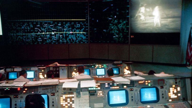 This July 20, 1969 photo made available by NASA shows the Mission Operations Control Room (MOCR) in the Mission Control Center (MCC), Building 30, during the Apollo 11 lunar extravehicular activity (EVA). The television monitor shows astronauts Neil A. Armstrong and Edwin E. Aldrin Jr. on the surface of the moon.