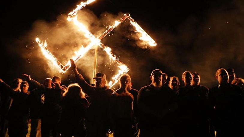 Members of the National Socialist Movement, a neo-Nazi group, hold a swastika-burning in Draketown, Ga., on April 21, 2018, following their rally that day in Newnan, Ga. An Ohio haunted house apologizes for hosting a Halloween ‘Swastika Saturday’ party.