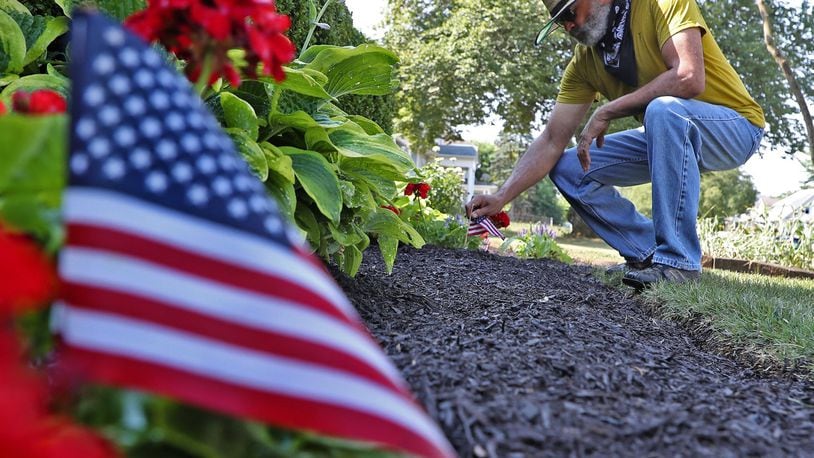 Dale Henry, president of the Gammon House, tends to the flowers in his front yard along Center Street Wednesday. BILL LACKEY/STAFF