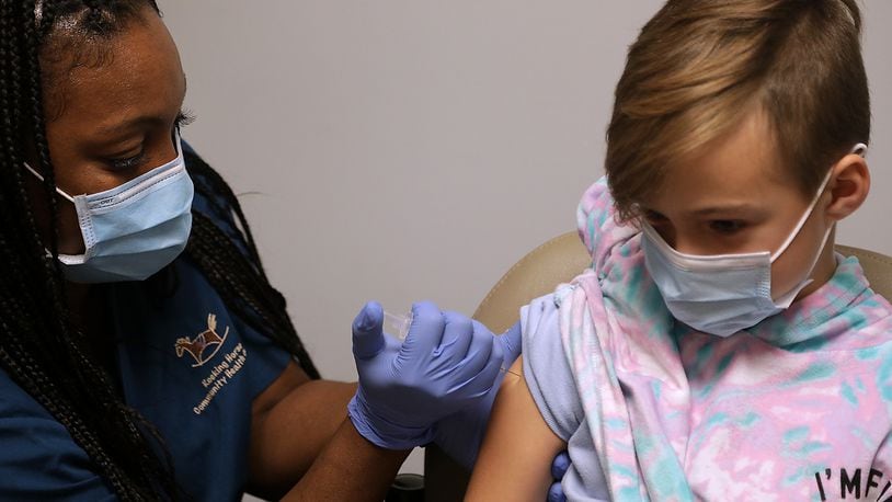 School districts in Clark and Champaign counties reported nearly 100 cases for the week of Nov. 15-21. Here, Poppy Tyler, 8, gets her COVID-19 vaccine shot at the Rocking Horse Center. BILL LACKEY/STAFF