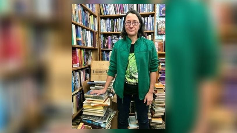 Kate Mooneyham, manager of Dark Star Books in Yellow Springs, stands next to a pile of books she plans to give away. SARAH FRANKS/CONTRIBUTED