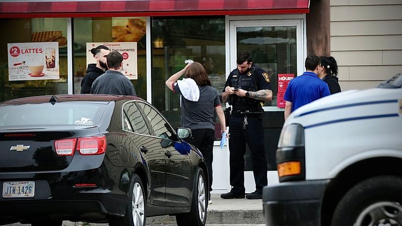 A member of the Springfield Police Division interviews employees of the Tim Horton’s on East Main Street on Monday morning, May 15, 2023, after a customer reportedly assaulted one of the employees. MARSHALL GORBY \STAFF