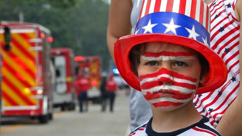 Corbin Buehler shows his patriotic spirit as he waits patiently along Enon-Xenia Road for more candy to be thrown his way during the annual Enon Fourth of July Parade last year. BILL LACKEY/STAFF